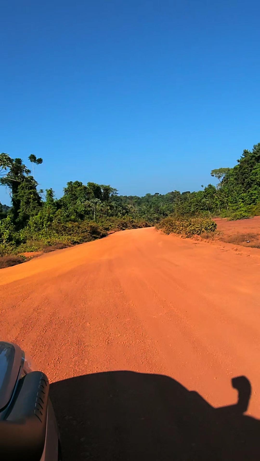 Red-dirt road through the rainforest leading to the site